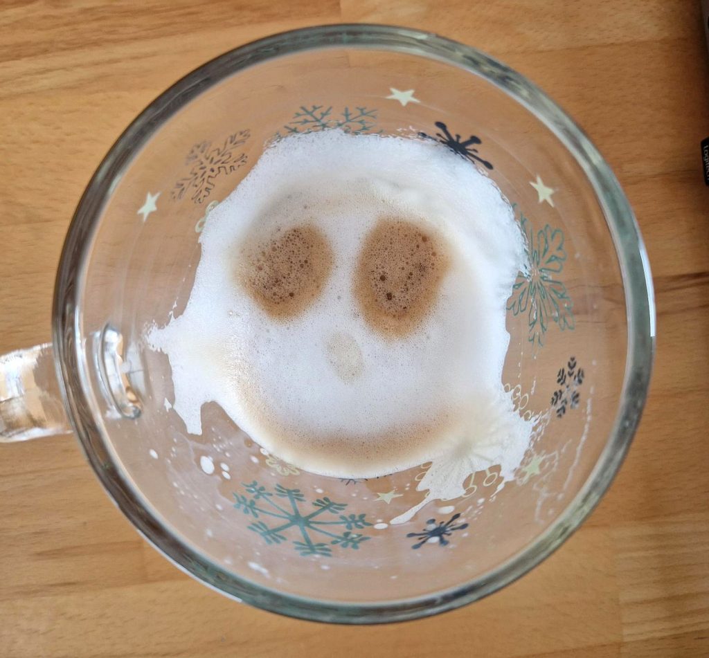 Der Rest Milchschaum im Glas zeigt das Gesicht eines Mädchens mit Zöpfen