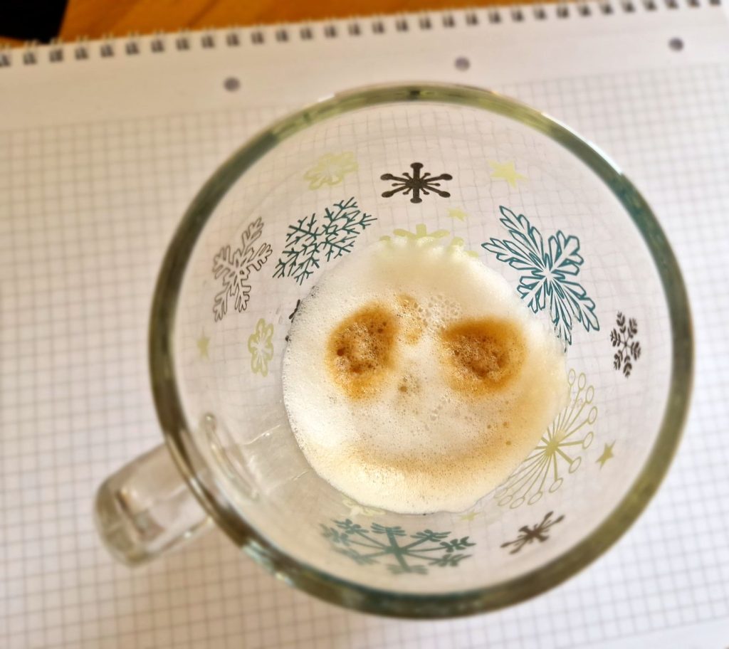 Ein Rest Milchschaum vom Cappuccino im Glas zeigt ein Gesicht