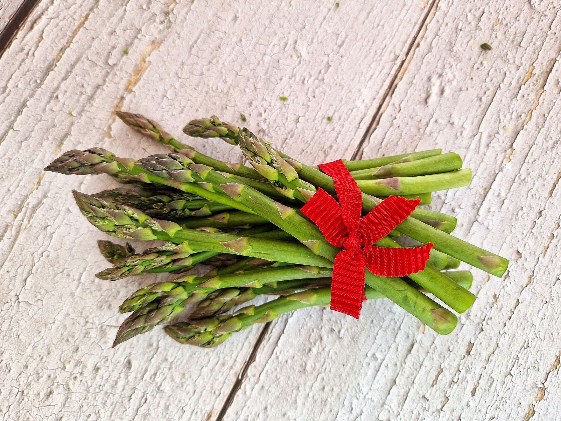Ein Bündel grüner Minispargel mit roter Schleife
