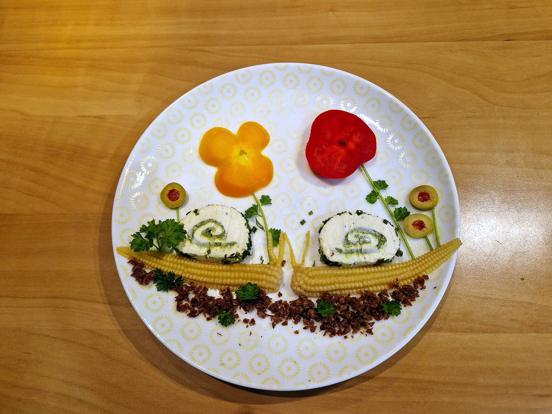 Ein Teller, auf dem mit verschiedenen Lebensmitteln Schnecken und Blumen gelegt wurden.