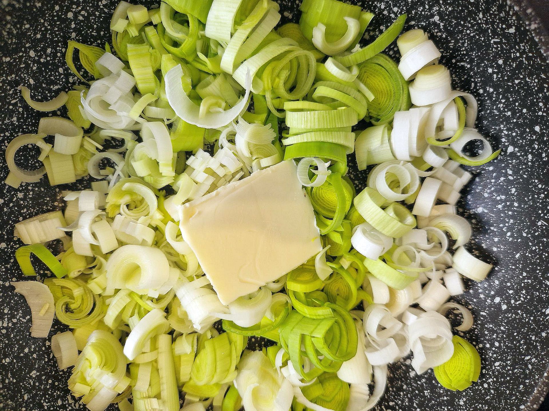 Lauchringe mit einem Stück Butter in einer Pfanne