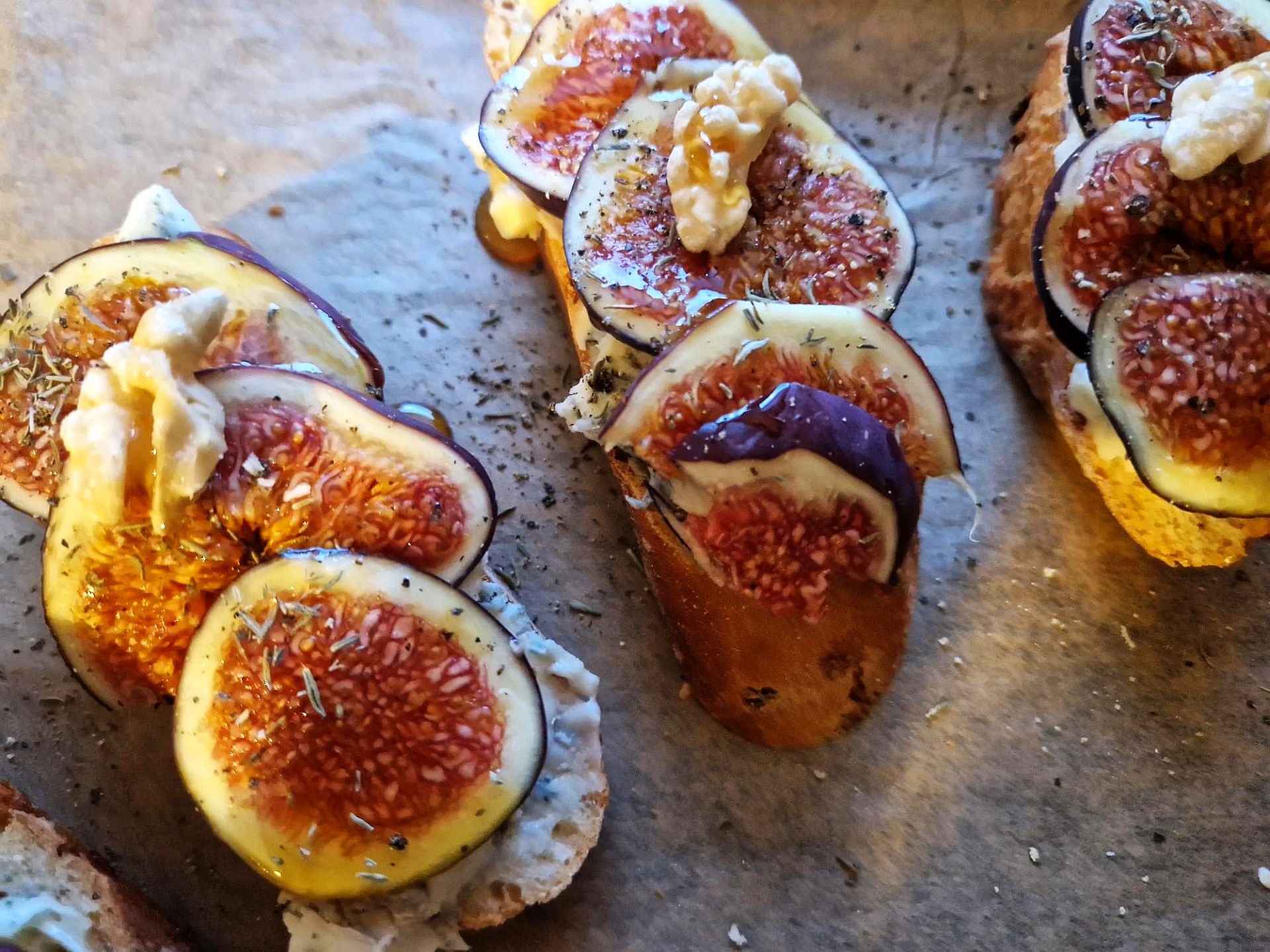 Baguettescheiben belegt mit Feigenscheiben, Gorgonzola, Walnuss, Thymian und Honig
