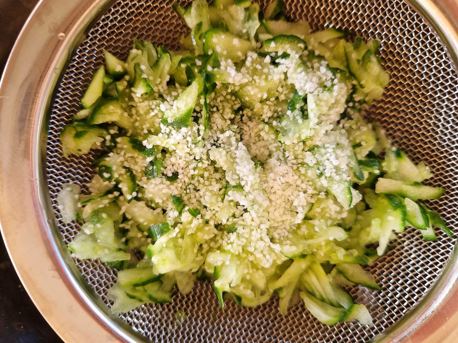Zucchini mit Salz Zucchiniraspeln in Sieb, mit Salz bestreut.