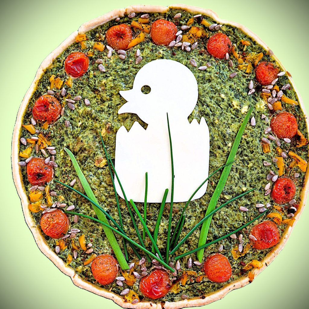 bild tarte ostern Quiche mit Spinat und Tomaten, dekoriert mit einem Küken aus Käse und Schnittlauchhalmen